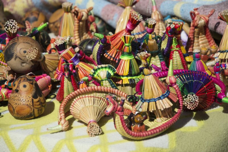 A close up view of a variety of vibrant handmade small boats made of reeds on a table outdoors