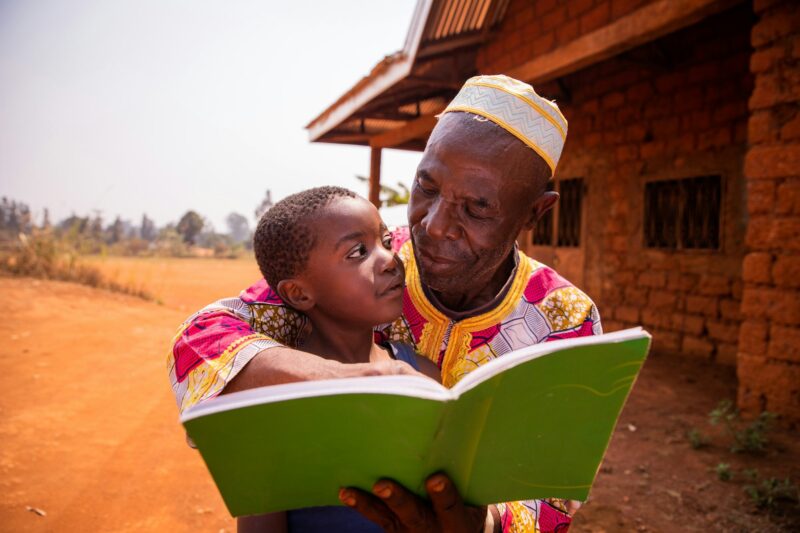 A grandfather reads fairy tales with his grandson in Africa, a moment of affection