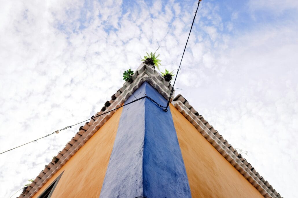A lone power cable crosses a street and reaches a corner of a colorful colonial