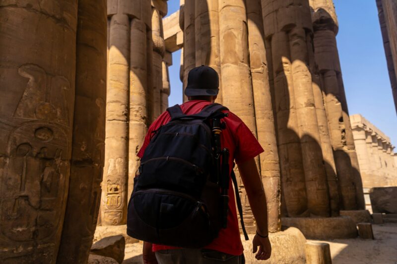 A photographer looking at ancient Egyptian drawings on the columns of the Luxor, Egypt
