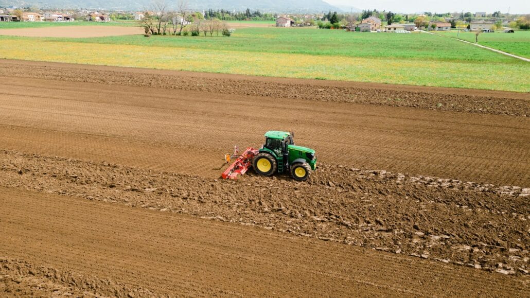 A picture of a rural farming community showcasing the use of farming machinery and equipment, such