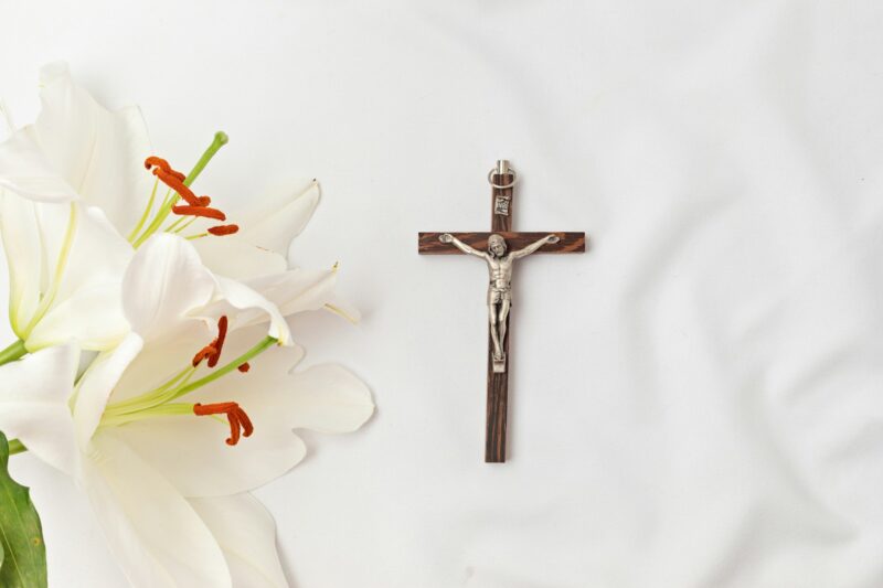 A symbolic Christian composition with christian cross lies beside a fresh white lily