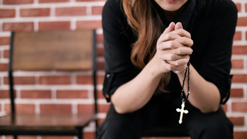 A young Asian Christian woman praying to Jesus Christ in a church.