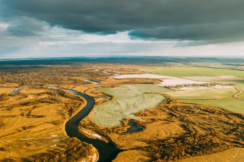 Aerial View Of Dry Grass And Partly Frozen Curved River Landscape