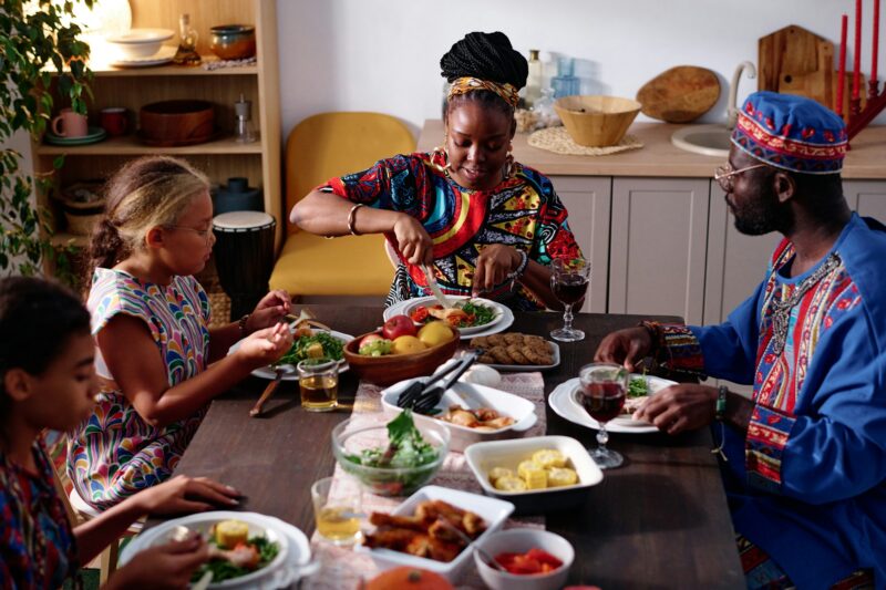 African American family of four in ethnic apparel sitting by festive table