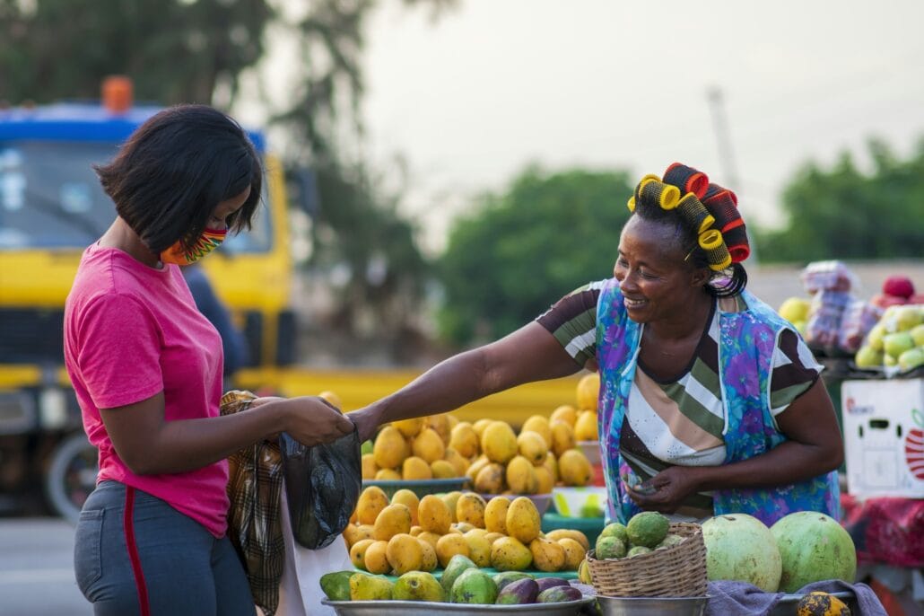African American female in a protective face mask shopping for fruit at a market