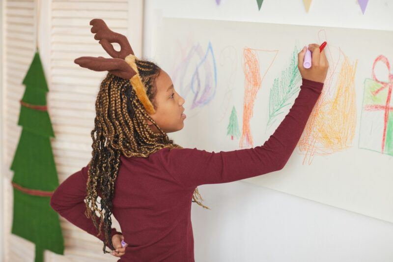 African-American Girl Drawing on Wall on Christmas