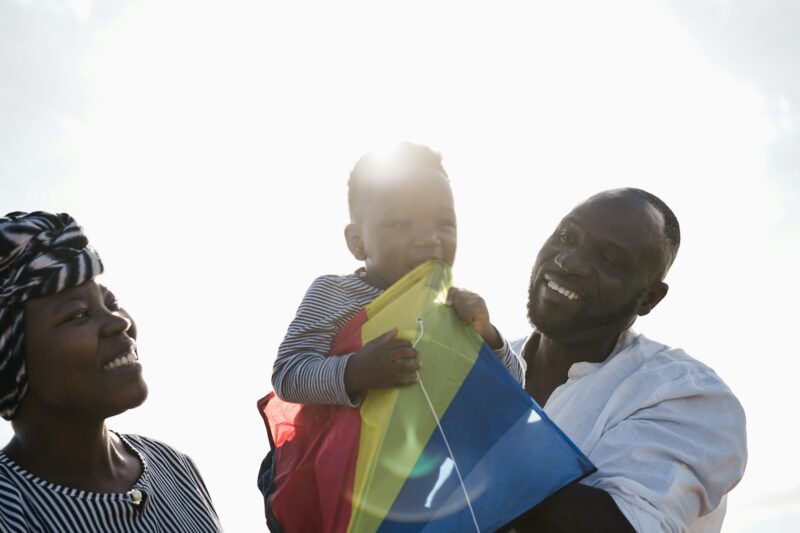 African family having fun with kite on the beach - Focus on father face