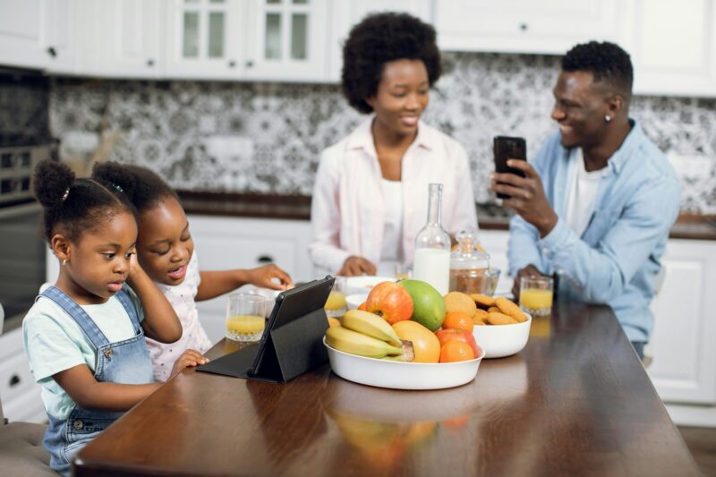 African family using mobile and tablet during breakfast