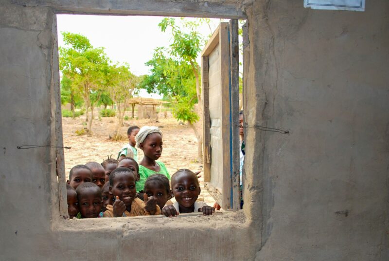 African kids peeking through the window of their schoolbuilding