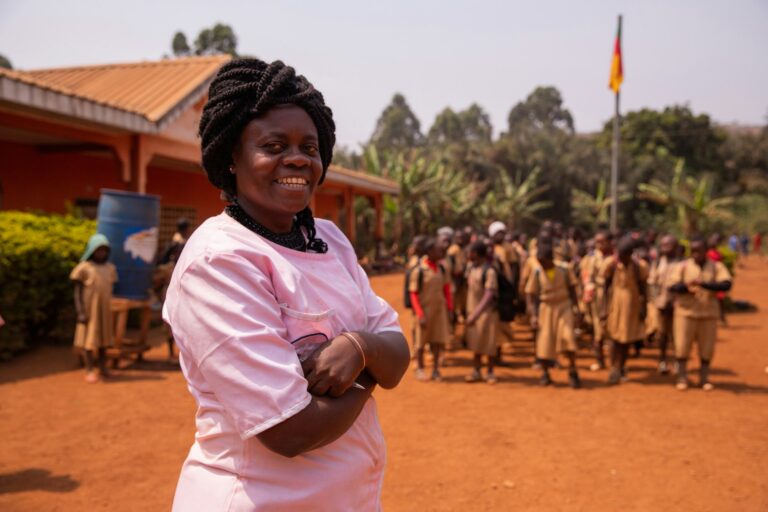 African school teacher following the pupils by singing the national anthem while raising the flag