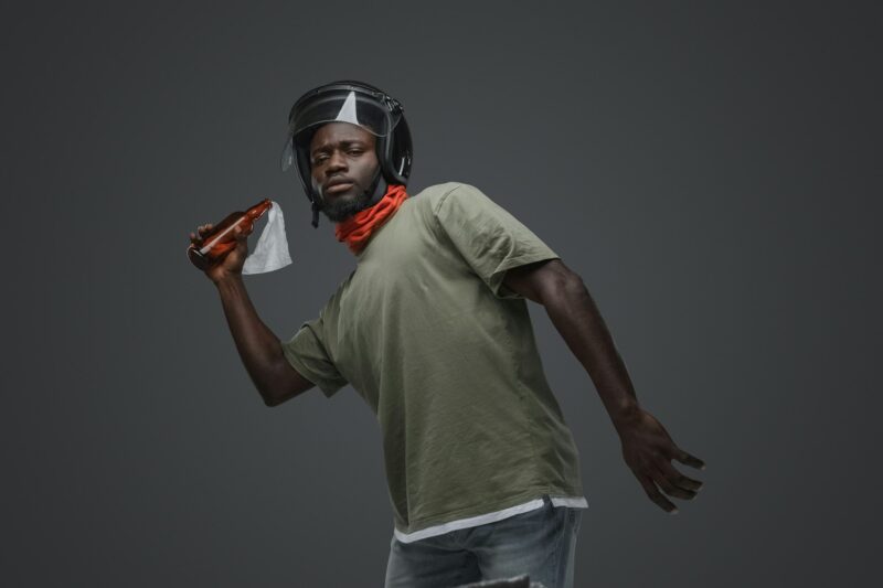 Aggressive african man throwing molotov coctail against gray background