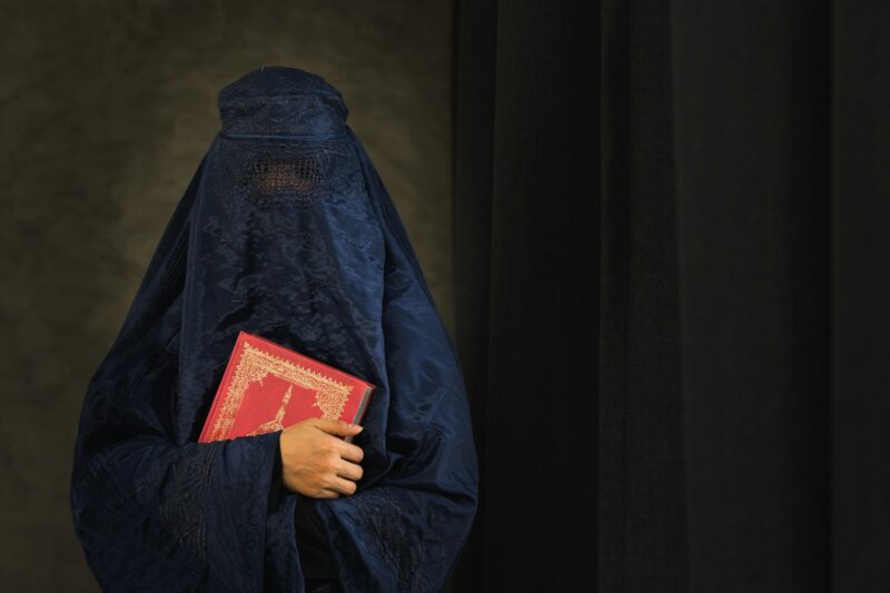 Asian women with burka reading the Islamic Quran