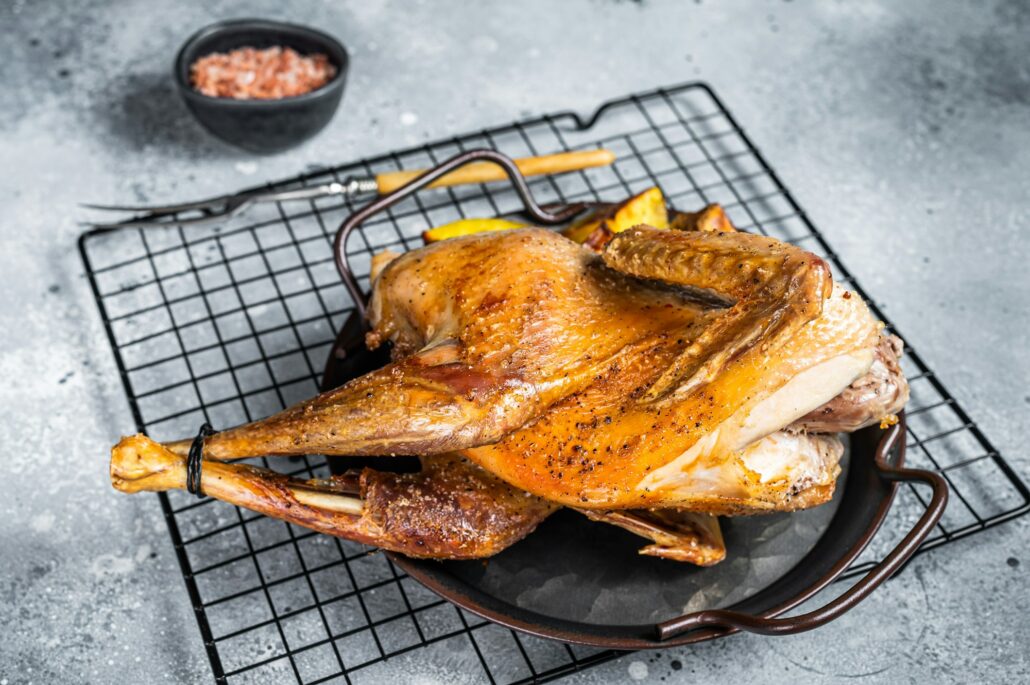 Baked Guineafowl, guinea fowl with potato in steel tray. Gray background. Top view