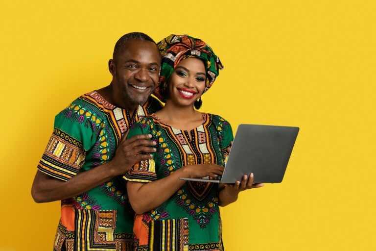 Beautiful black couple checking content on laptop, yellow background