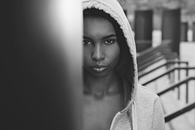 Black and white photo of beautiful young sportswoman in hood looking at camera