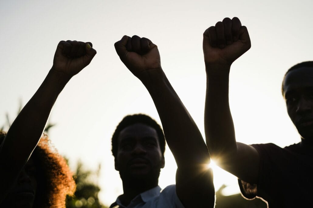 Black demonstrator people holding hands against racism protest - Focus on fists