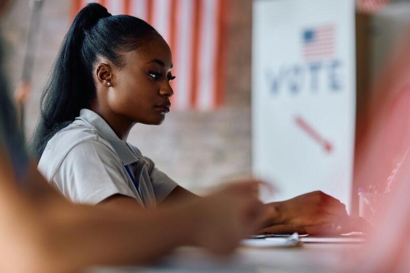 Black female volunteer at polling place during US elections.