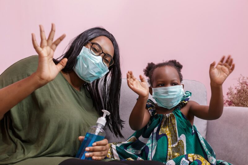 Black people' mother and daughter wearing a mask are washing hands with alcohol