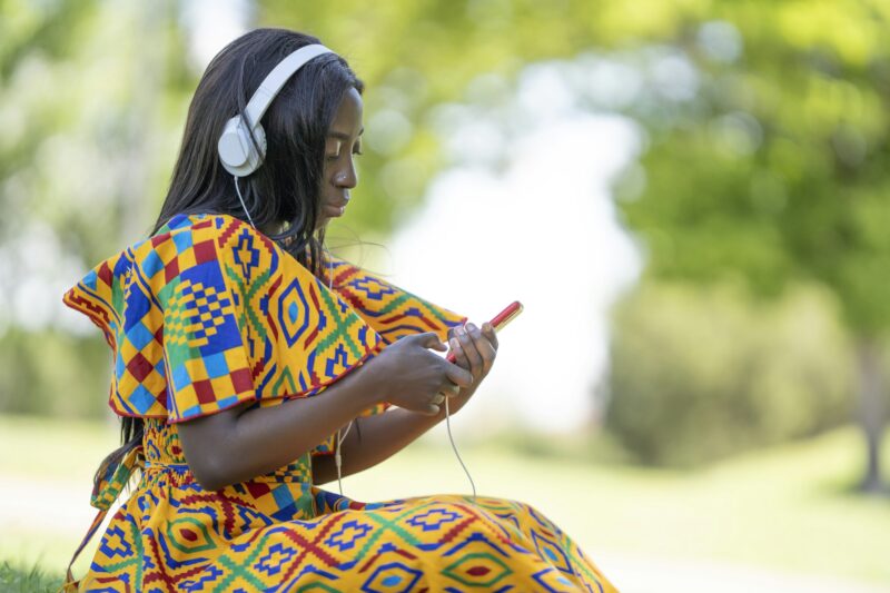 Black skinned woman using mobile phone with headphones