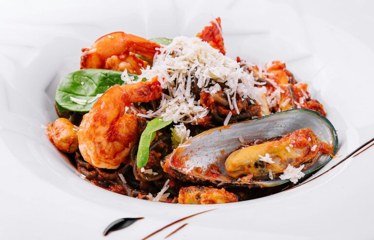 black spaghetti with seafood on white plate