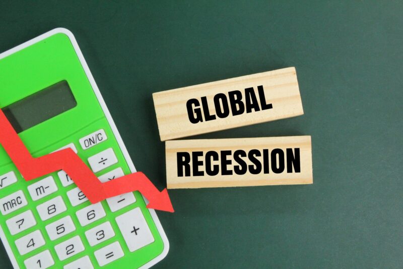calculator, red arrow down and stay with the word global recession. market down concept.
