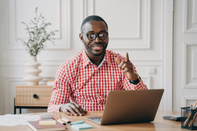 Cheerful Afro-American male English language tutor having remote classes online