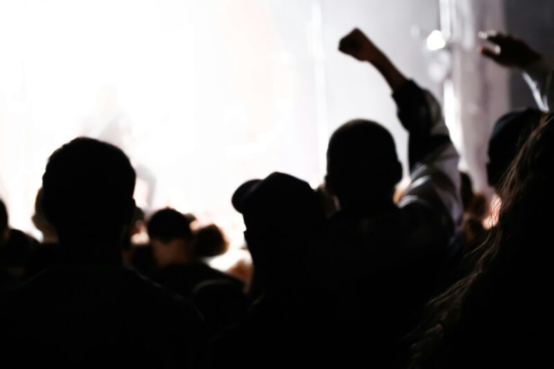 Cheering crowd and stage lights with space for your text. Defocus silhouette of people raise hand up