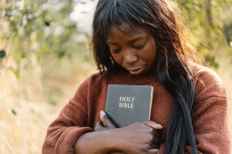 Christian afro girl holds bible in her hands.