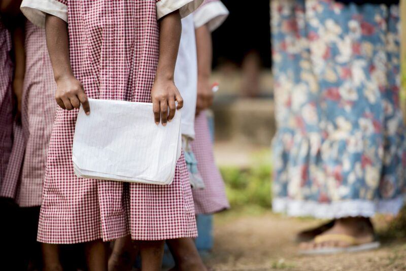 Close shot of kids standing in line for school and holding their notebooks with blurred background