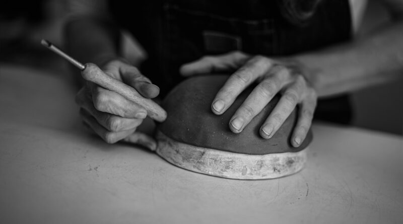 Close up female potter modeling clay bowl in workshop - Artisan work and creative craft concept