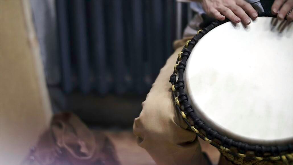 Close up of hands of a black man playing a drum. Clip. Drummer plays on small African drum, closeup