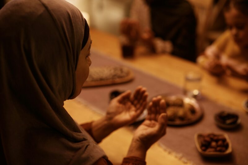 Close up of Middle Eastern woman during family prayer at dining table.