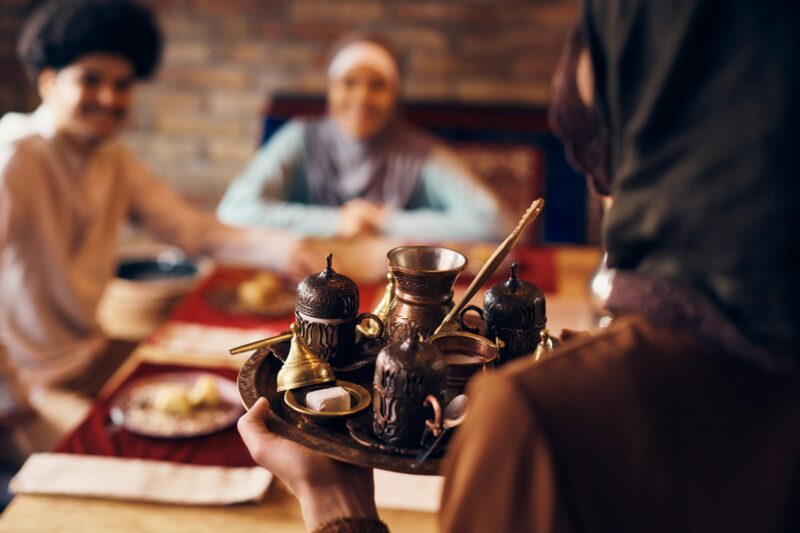 Close-up of Middle Eastern woman serving traditional Arabic coffee at home