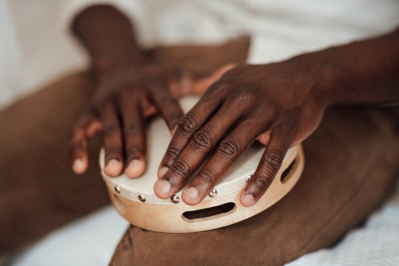 Close up of musician black man hands playing on rustic tambourine