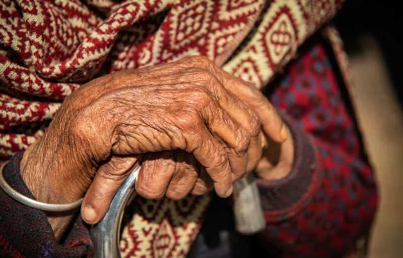 Close up of the crossed wrinkle hands of an elder grandmother nepalese woman