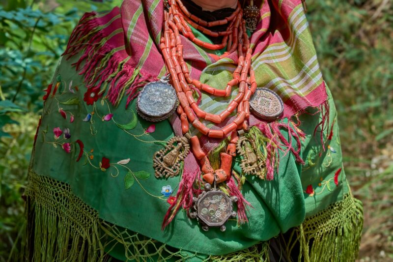Close-up shot of a Maragato elderly woman in a traditional green Castilla y Leon costume and jewelry