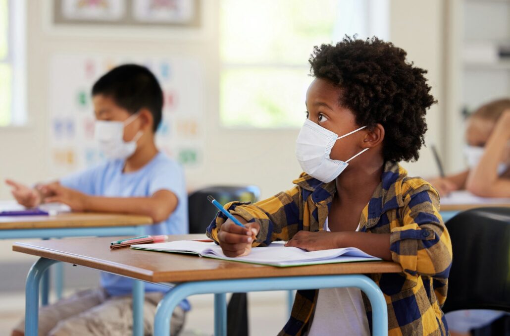 Covid, education and learning with a student in class, writing and studying at a school while weari
