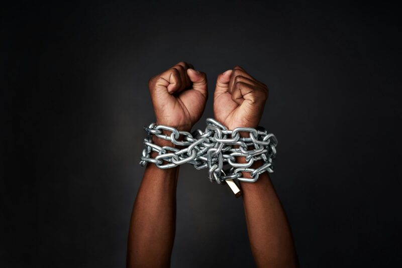 Cropped shot of a mans hands tied up with chains against a black background