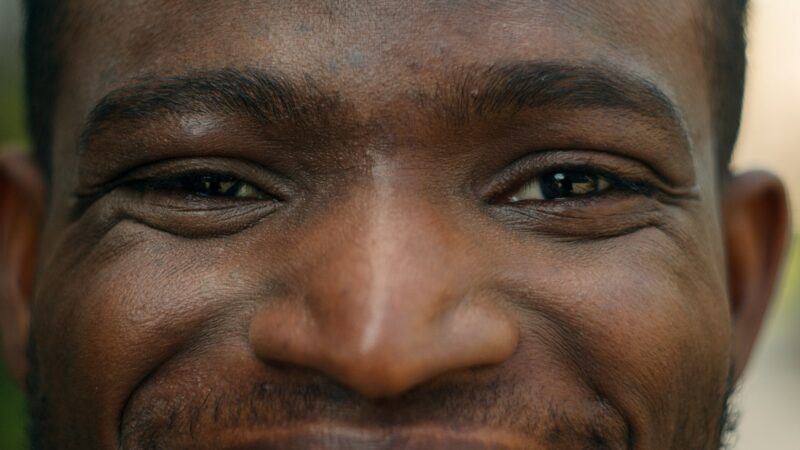Cropped view close up male eyes African American smiling happy carefree man ethnic joyful male