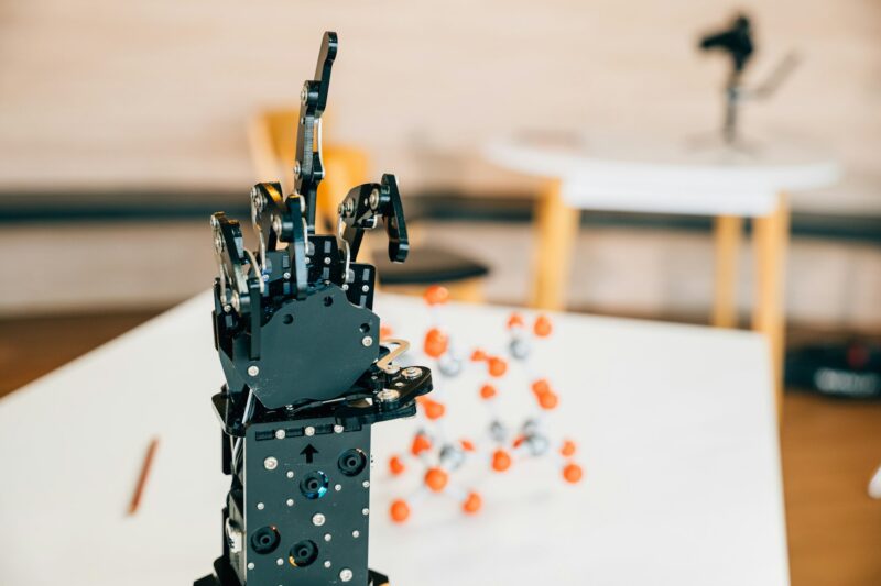 Cyborg mechanical arm features a black real robot hand making contact on a table. Representing