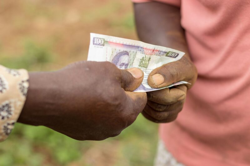 Farmers (man and woman) exchanging money in Kenyan shilling currency