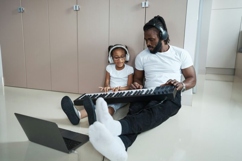 Father and daughter play musical instrument on floor in room