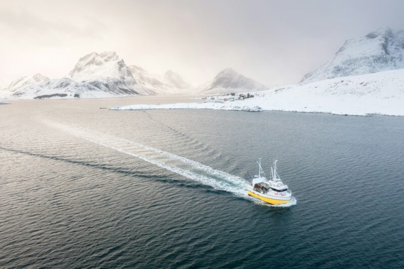 Fishing boat in the fjord. Aerial view of Lofoten Islands, Norway. Industrial fishing.