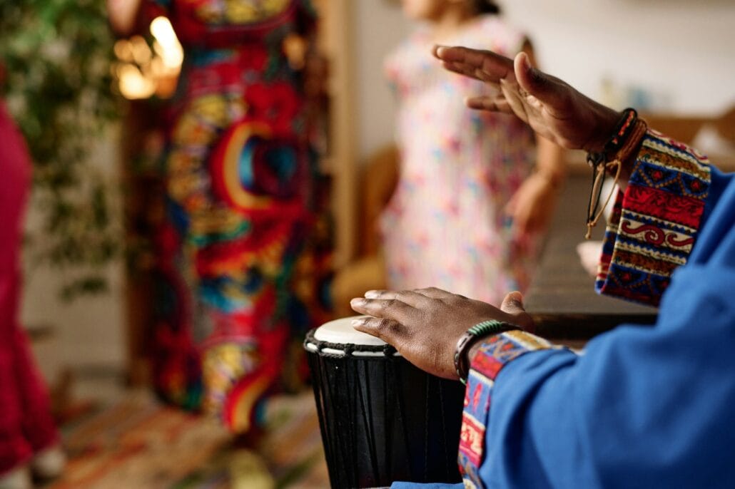 Focus on hands of young African American man in costume beating drum
