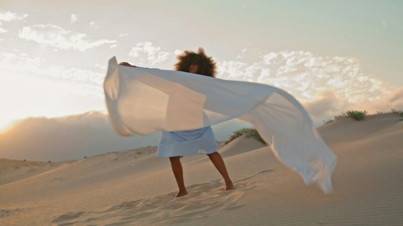 Girl dancer waving fluttering cloth performing contemporary dance in desert.