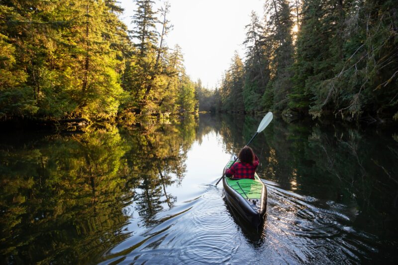 Girl kayaking in the river during a sunny summer morning