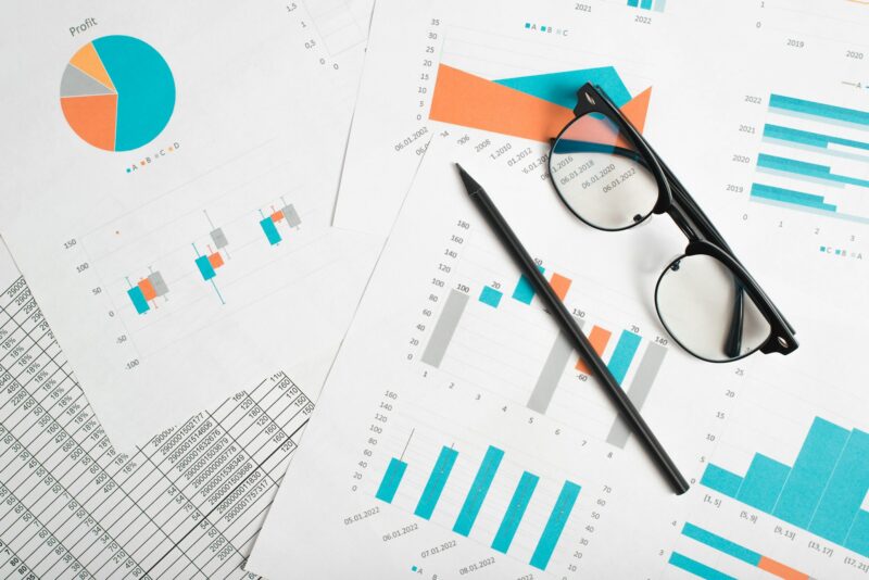 Glasses, pencil, business documents with infographics and economic indicators