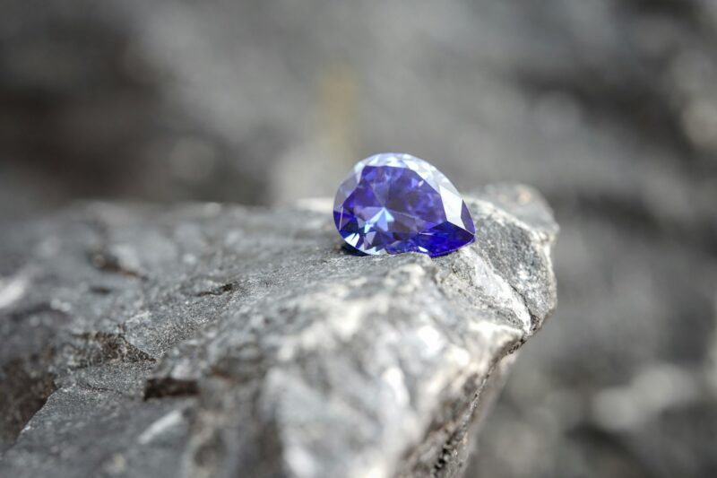 Glimmering natural purple sapphire gemstone on a rock surface