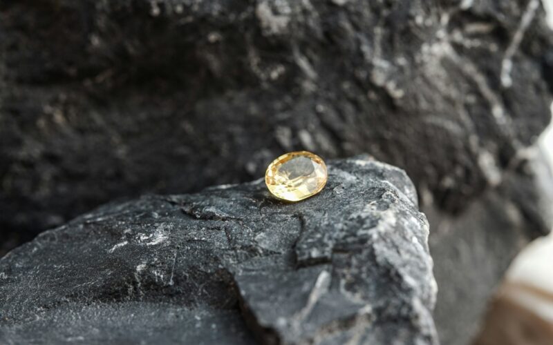 Glimmering natural yellow sapphire gemstone on a rock surface